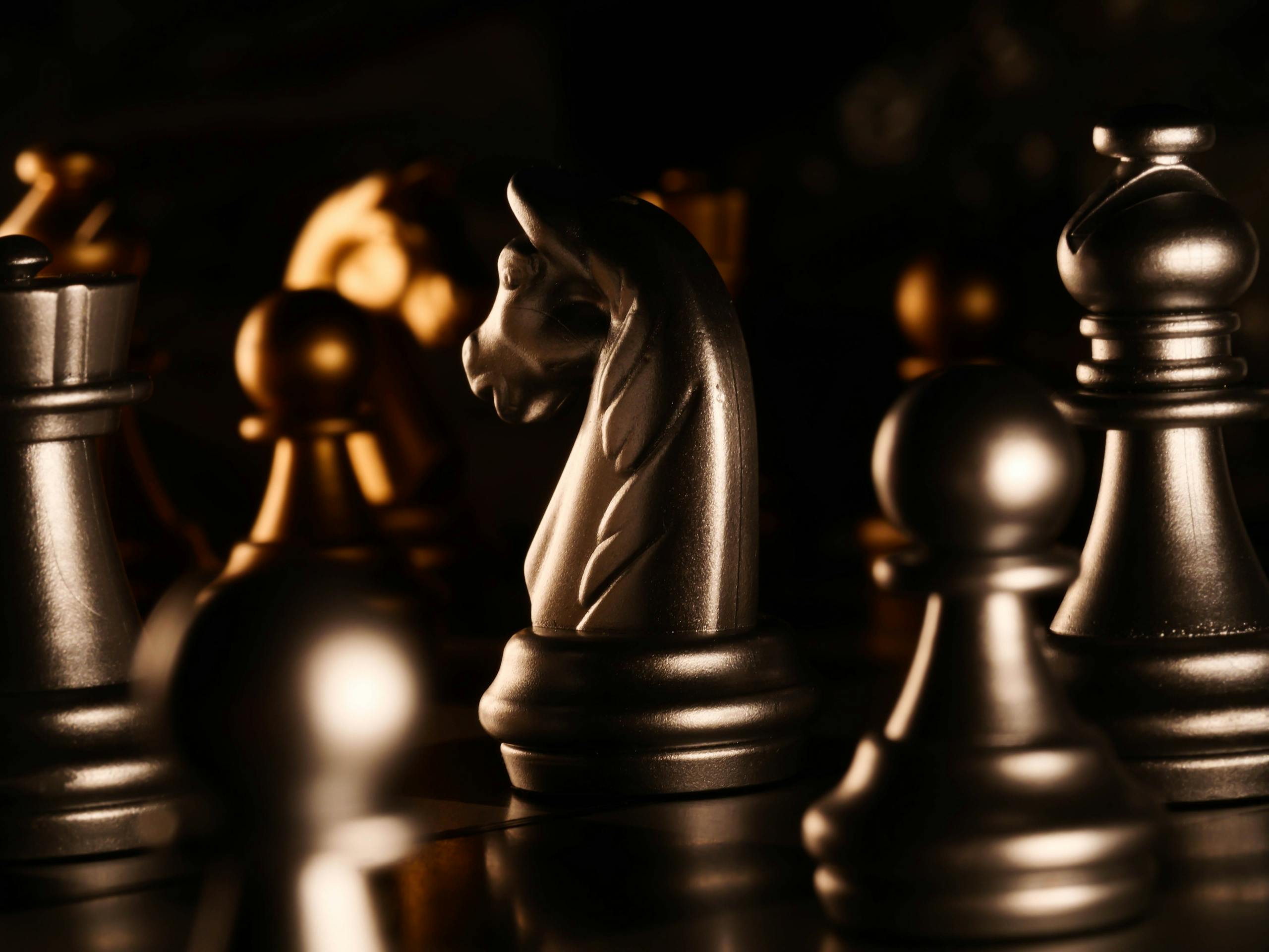 Detailed close-up of metallic chess pieces on a chess board highlighting strategy and focus.